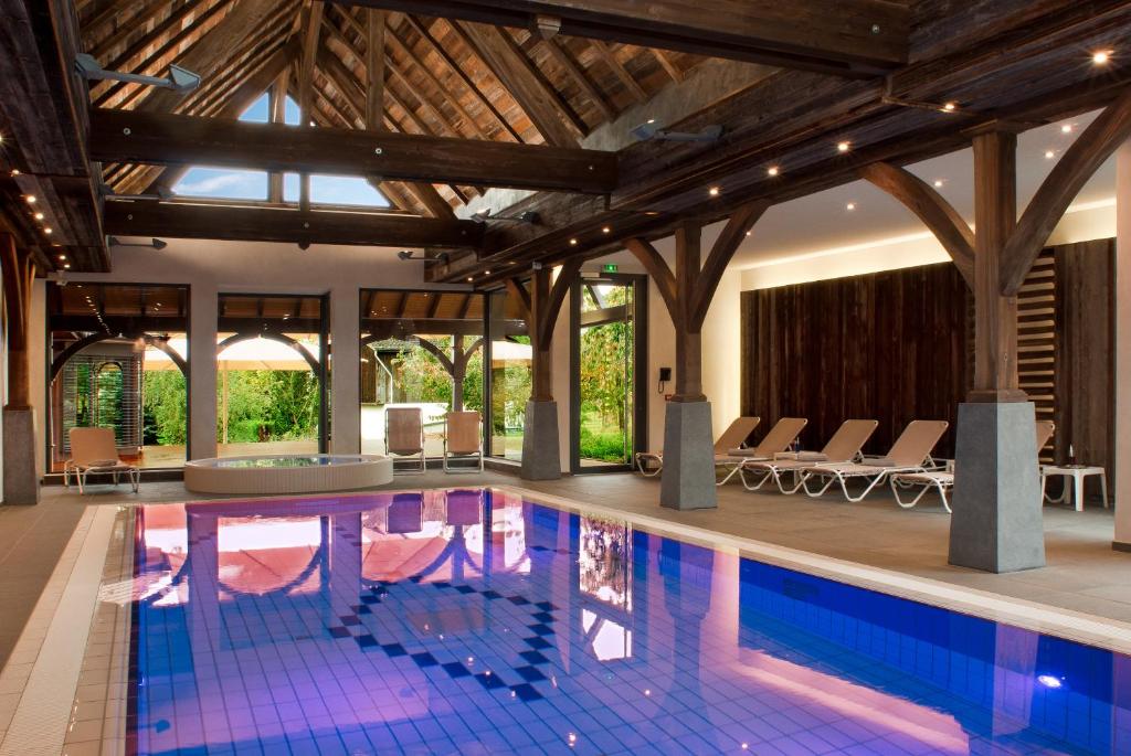 a large swimming pool with chairs in a building at Logis Hotel Le Parc & Spa in Saint-Hippolyte