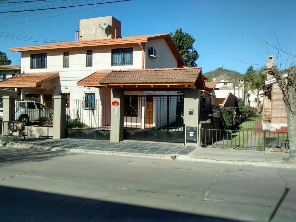 a white house with a red roof on a street at Complejo Camila in Villa Carlos Paz