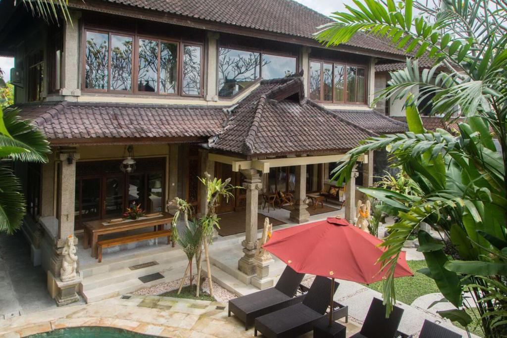 a house with a red umbrella in front of it at Lily Lane Villas in Ubud