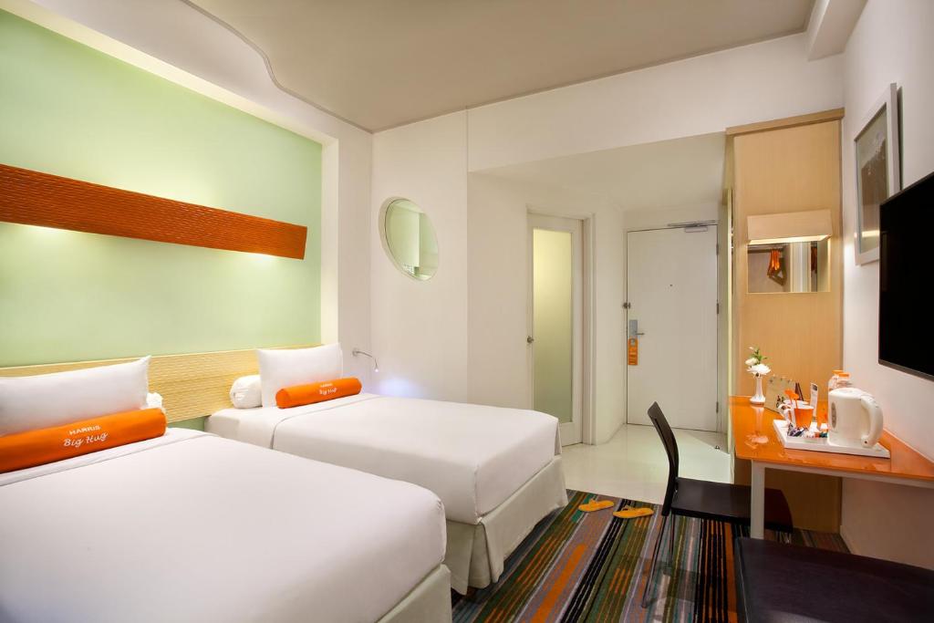 a hotel room with two beds and a desk at HARRIS Hotel & Convention Festival Citylink Bandung in Bandung