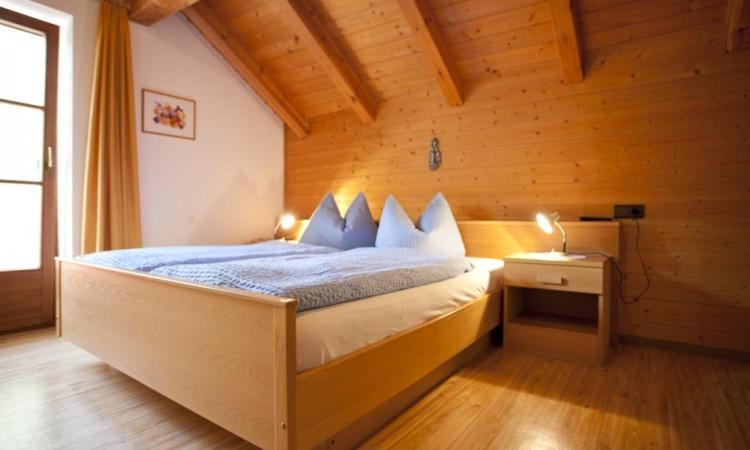 um quarto com uma cama num quarto de madeira em Huberhof em Bressanone