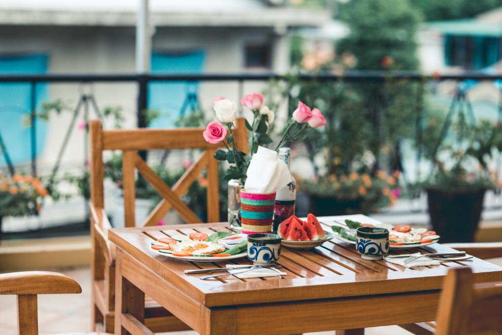 einen Holztisch mit Teller mit Lebensmitteln und Blumen darauf in der Unterkunft The HillSide Homestay Hue in Hue