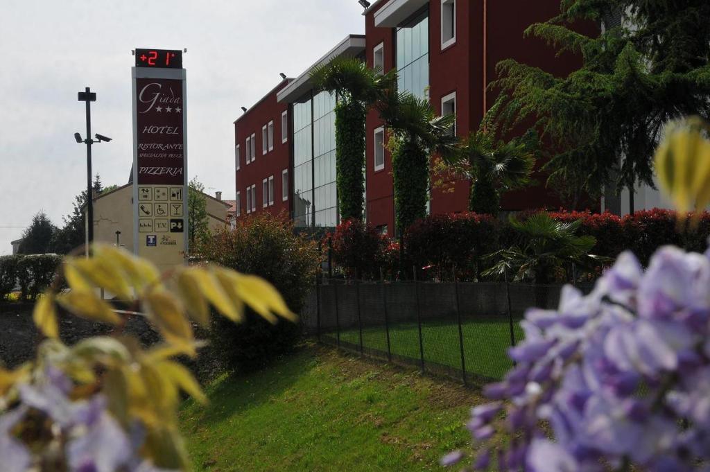 a building with a clock tower and purple flowers at Hotel Ristorante Giada in Grumolo delle Abbadesse