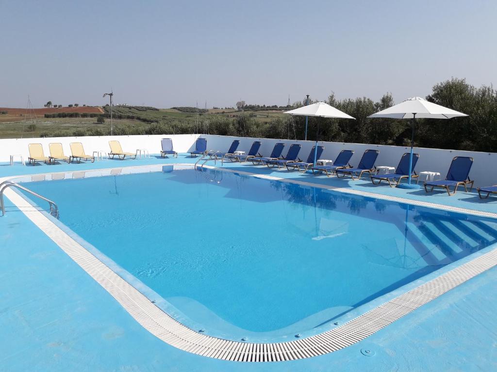 a large blue swimming pool with chairs and umbrellas at Villagiannis in Nea Fokea