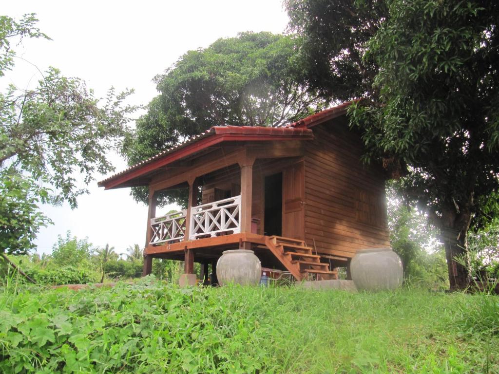 uma pequena cabana de madeira numa colina com um alpendre em Don Som Riverside Guesthouse em Don Som