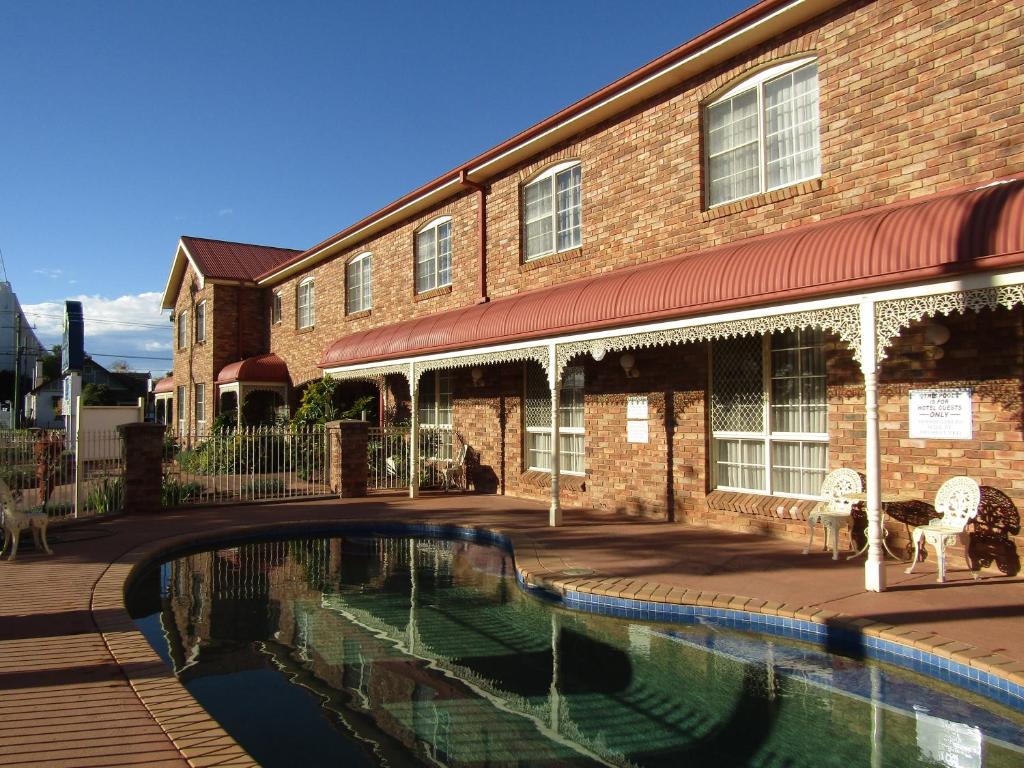 a swimming pool in front of a brick building at Australian Heritage Motor Inn in Dubbo