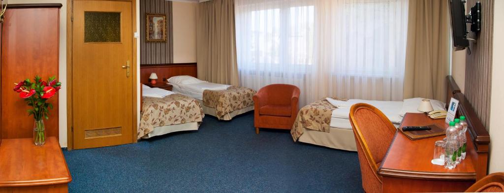 a hotel room with two beds and a desk at Załęże in Katowice
