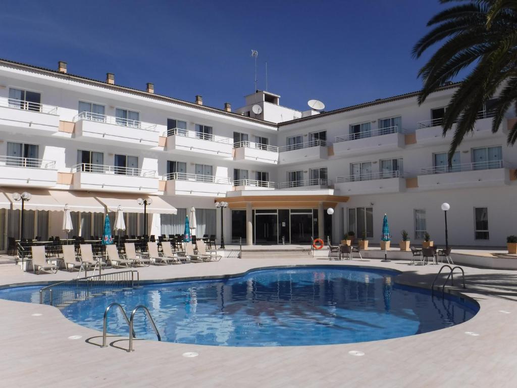 a hotel with a swimming pool in front of a building at Maracaibo Aparthotel in Can Picafort