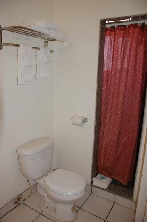 a bathroom with a toilet and a red shower curtain at HWY Express Inn and Suites in Thatcher