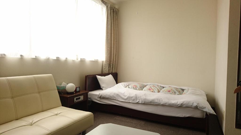 a bedroom with a bed and a couch and a window at Weekly Mansion Ise Annex in Ise