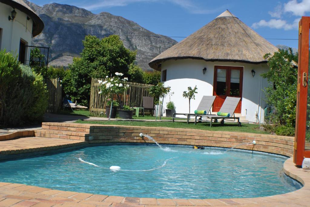 een zwembad met een gebouw en een huis bij Roundhouse Guesthouse in Franschhoek