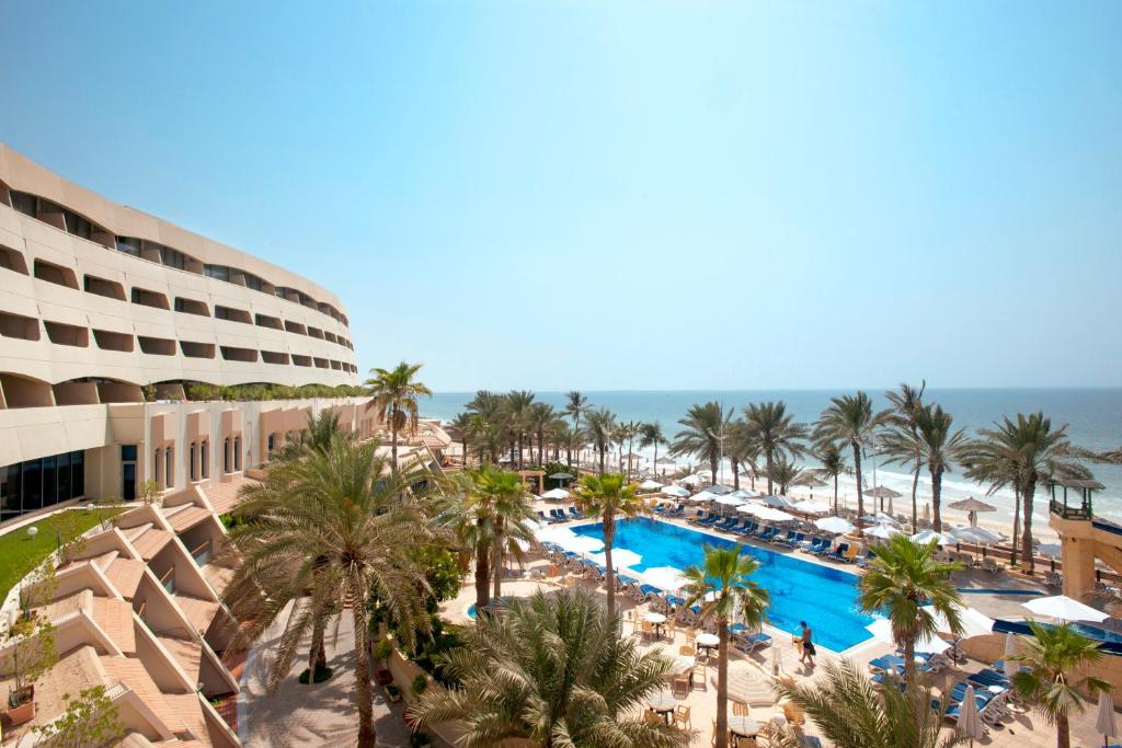 an aerial view of a resort with palm trees and a pool at Occidental Sharjah Grand in Sharjah