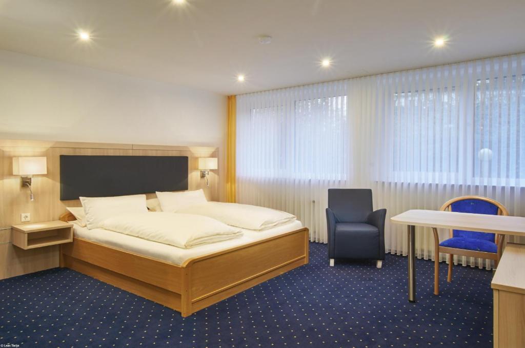 a bedroom with a bed and a desk and a chair at Hotel BonaMari in Salzgitter