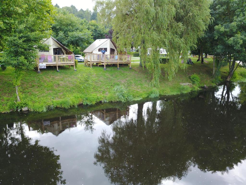 a couple of cottages next to a river at camping des ribieres in Confolens