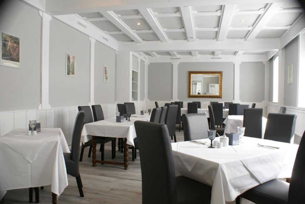comedor con mesas, sillas y espejo en Hotel Garni Alte Post, en Boffzen