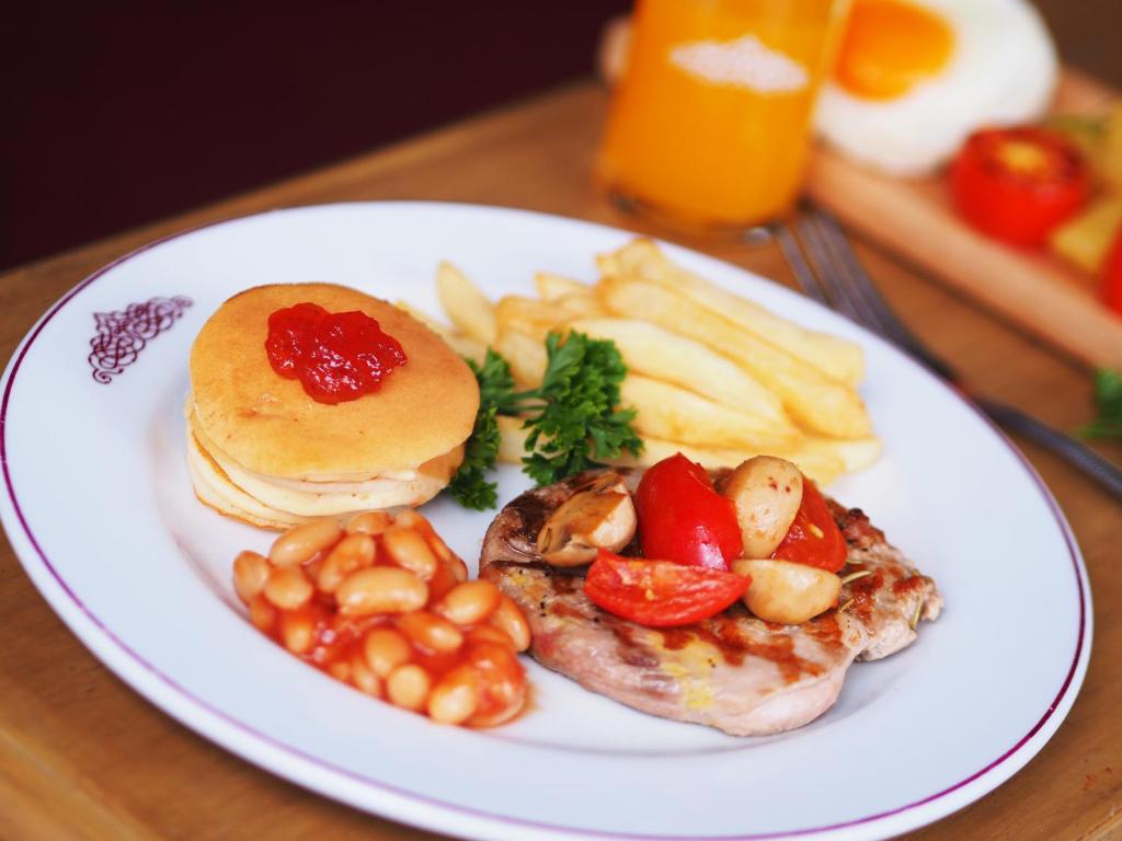 A full plated breakfast with eggs, bacon, beans, mushrooms, tomatoes and fries.