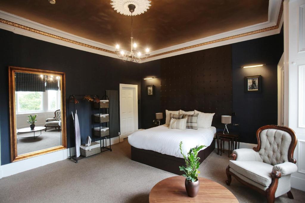 a bedroom with a bed and a chair and a mirror at The Belhaven Hotel in Glasgow