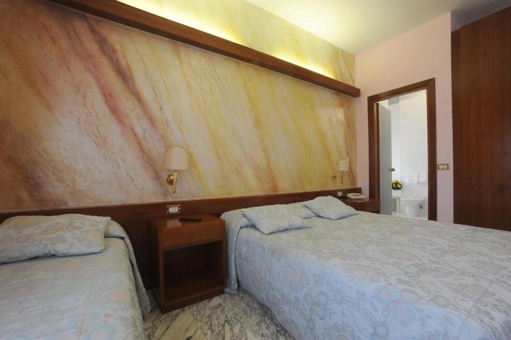 1 dormitorio con 2 camas y pared de madera en Hotel Excelsior, en Latina