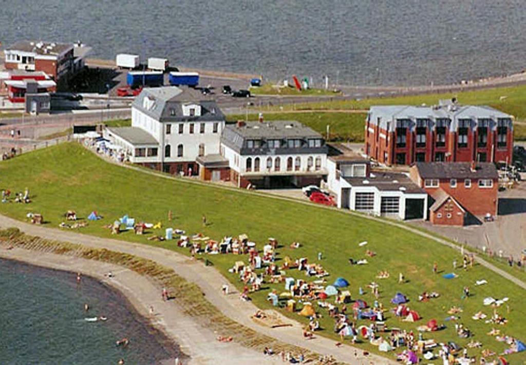 eine Gruppe von Menschen, die auf einem Hügel in Strandnähe sitzen in der Unterkunft Strandhotel Dagebüll direkt an der Nordsee in Dagebüll