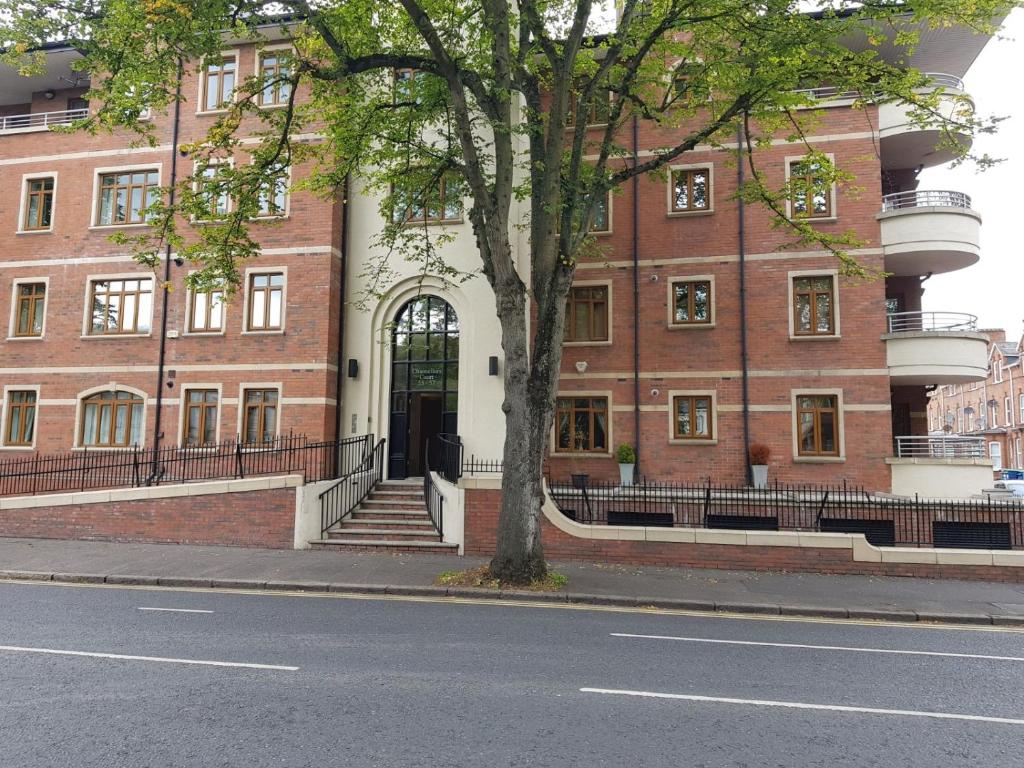 un gran edificio de ladrillo con un árbol delante de él en Chancellors court en Belfast