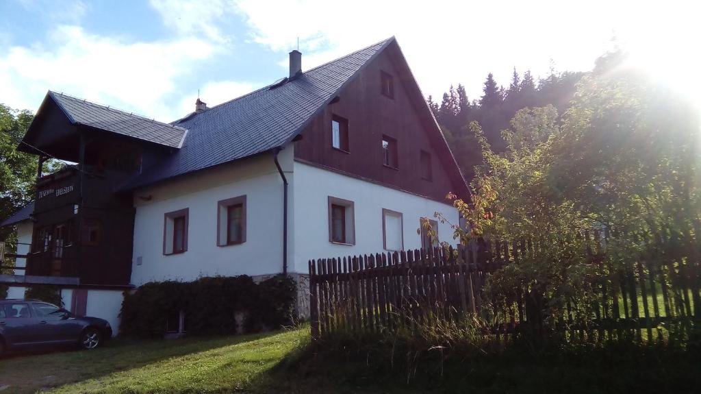 ein weißes und rotes Haus mit einem Zaun und einem Auto in der Unterkunft Penzion Edelštejn in Petrovice