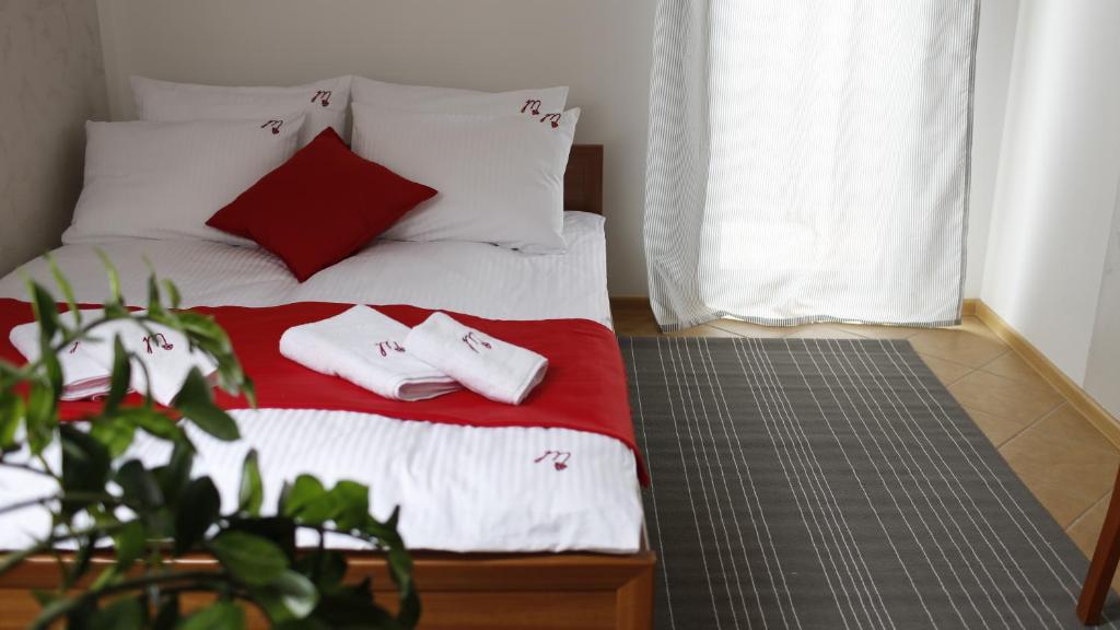 Schlafzimmer mit einem Bett mit roten und weißen Kissen in der Unterkunft Malinowe Lato in Grzybowo