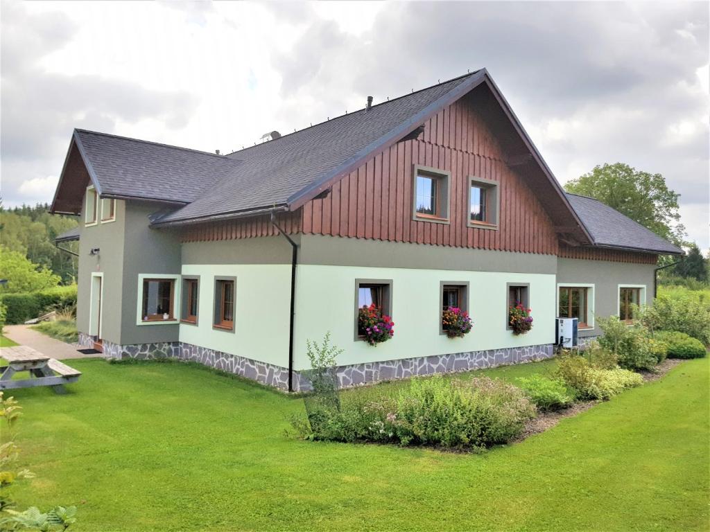 a house with a red roof and a green yard at Apartmány Sára in Tanvald