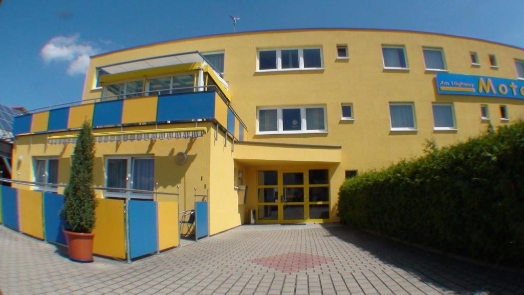 a yellow and blue building with a sign on it at Motel Am Highway in Althengstett