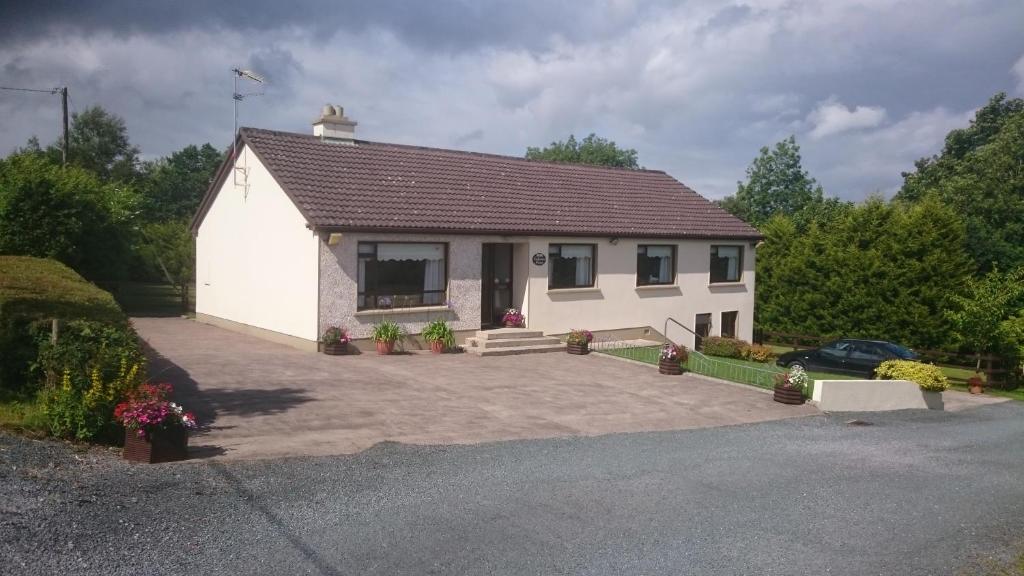 a small white house with a driveway at Lakeview House in Ballinamore