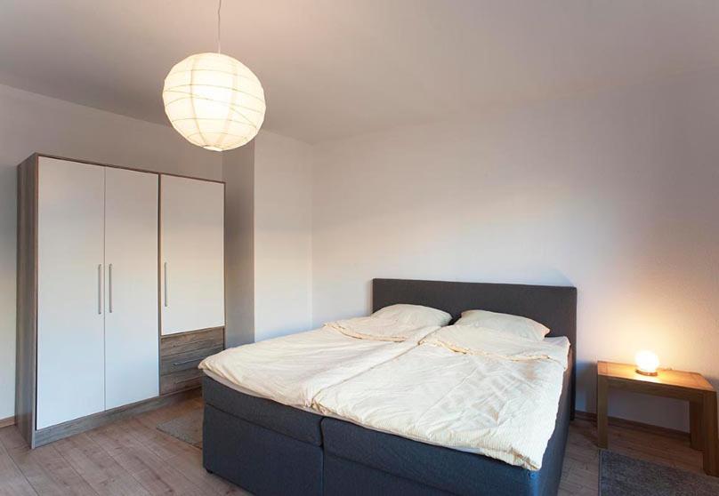 a bedroom with a large bed and a lamp at Apartments Zentrum Brühl in Leipzig