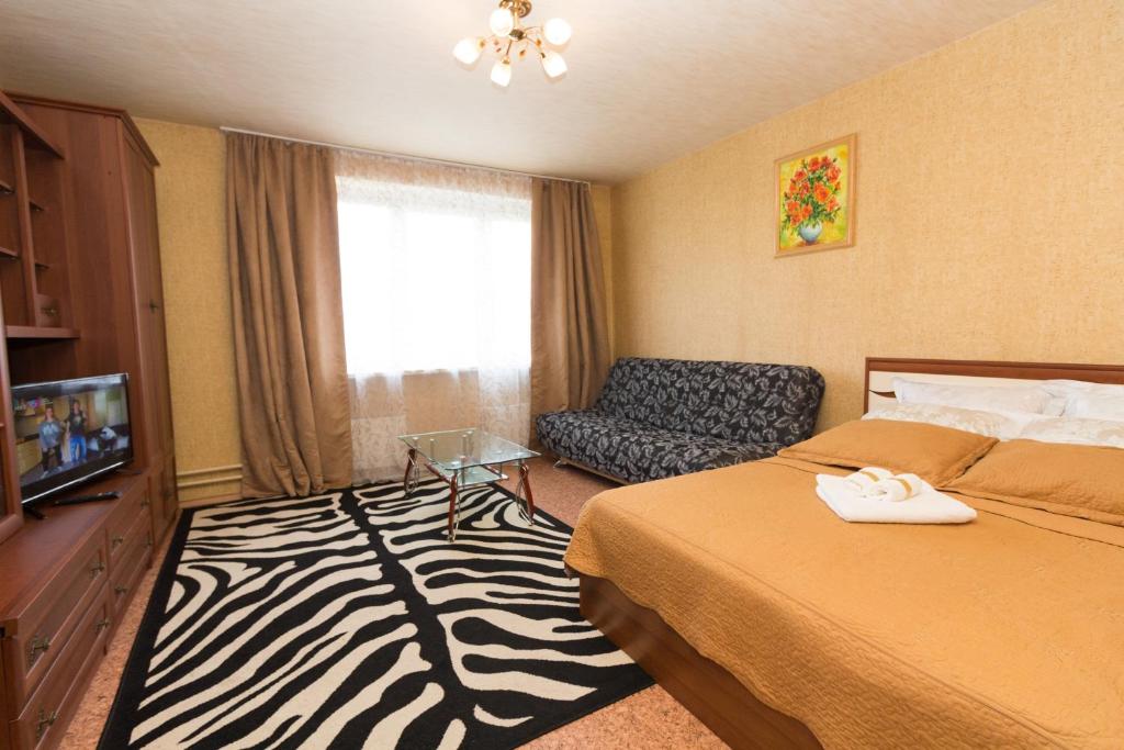 モスクワにあるApartments on Molodogvardeyskayaのベッド、椅子、テレビが備わるホテルルームです。