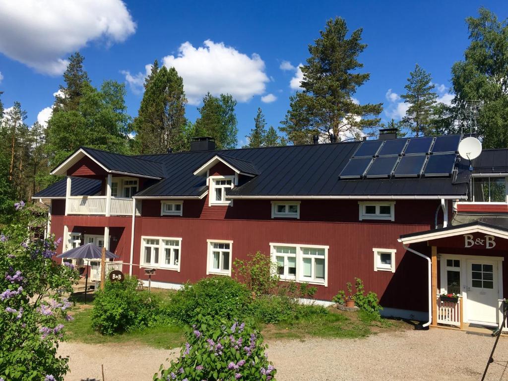 ein rotes Haus mit Sonnenkollektoren auf dem Dach in der Unterkunft Purola Farm Guesthouse in Saarijärvi
