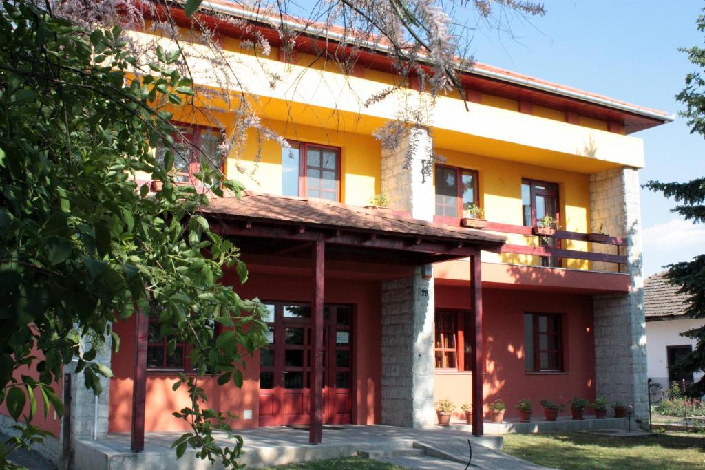 トカイにある5 Puttonyos Vendégházの木の大きな黄色と赤の建物