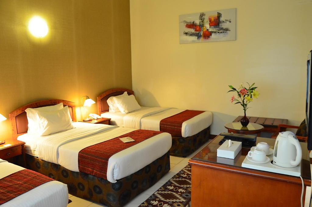 a hotel room with two beds and a table at Nejoum Al Emarat in Sharjah