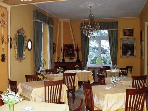 a dining room with tables and chairs and a chandelier at Hotel Villa Ruscello in Baveno