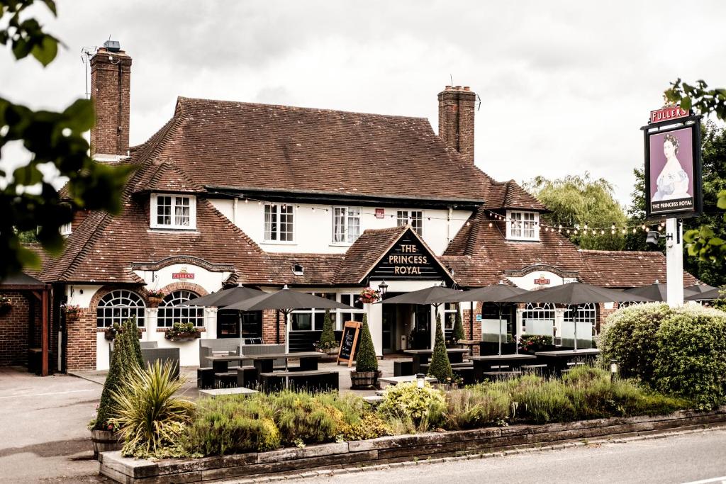 a restaurant with tables and umbrellas in front of a building at The Princess Royal in Farnham