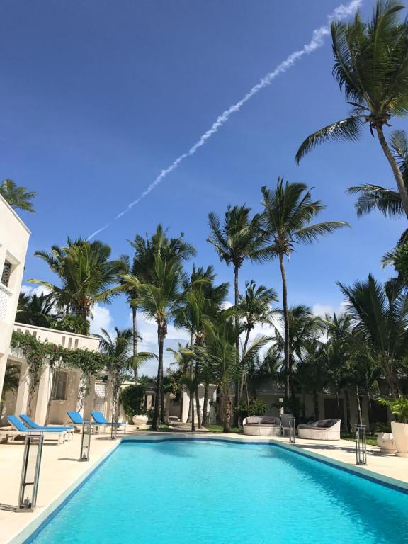 una piscina en el complejo con palmeras en The Villa Luxury Suites Hotel, en Diani Beach