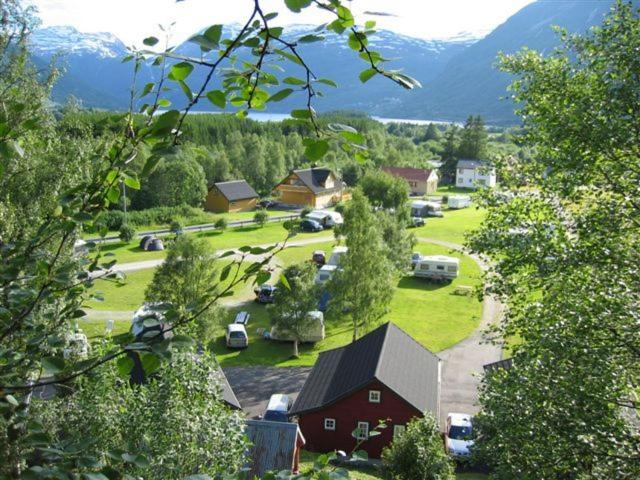 a farm with a red barn and cars in a field at Røldal Hyttegrend & Camping in Røldal