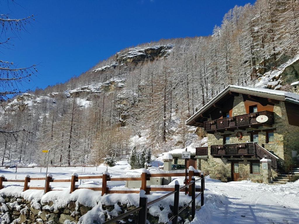 drewniany domek na śniegu obok płotu w obiekcie Chalet La Garde w mieście Valtournenche