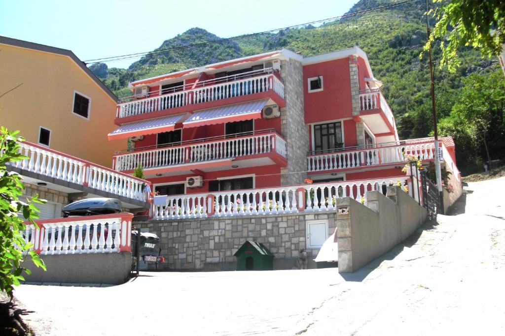 a red building with white balconies on the side of it at Apartments Simun in Kotor