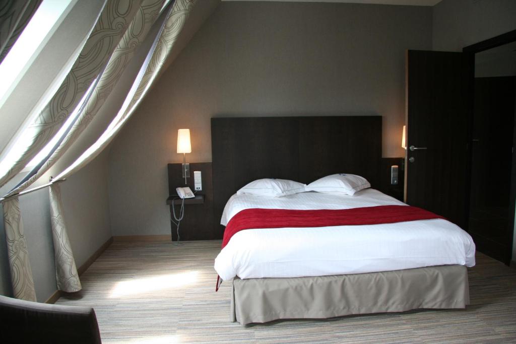 a bedroom with a large bed with white sheets and red blanket at Biznis Hotel in Lokeren