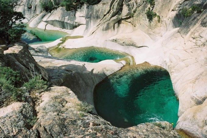 a pool of emerald green water in a rocky canyon at Residence ACQUA LINDA Porticcio in Porticcio