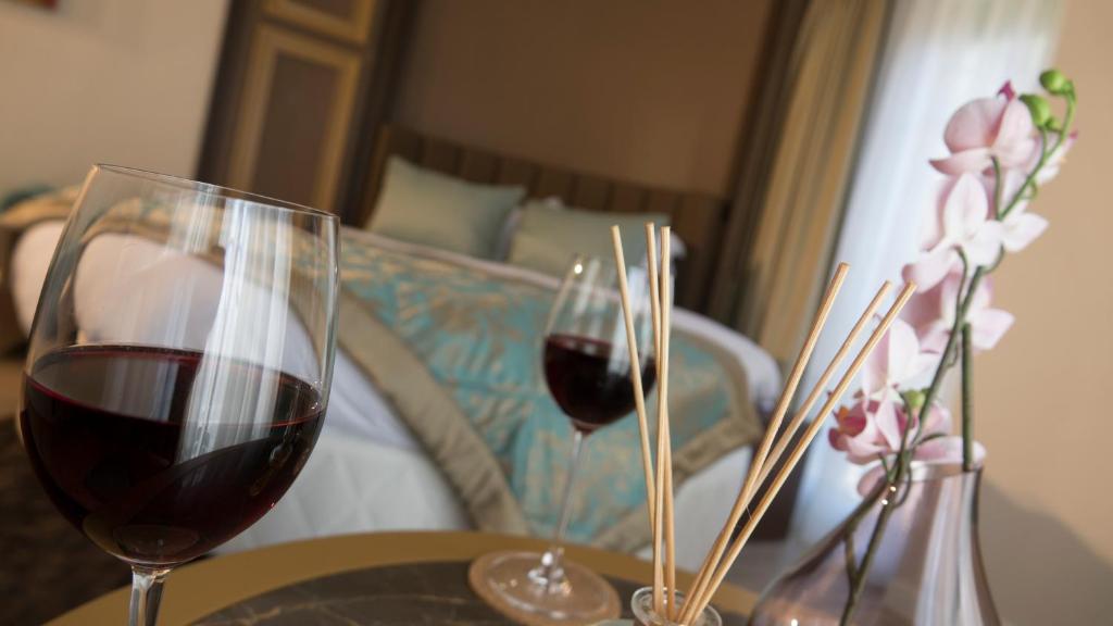 Dois copos de vinho tinto numa mesa com uma cama. em The Escape Hotel em Ağva