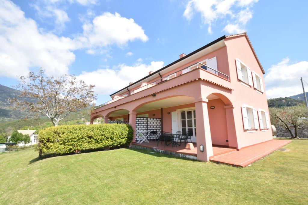 une maison rose avec une pelouse devant elle dans l'établissement Case Vacanze Malonghe, à Deiva Marina