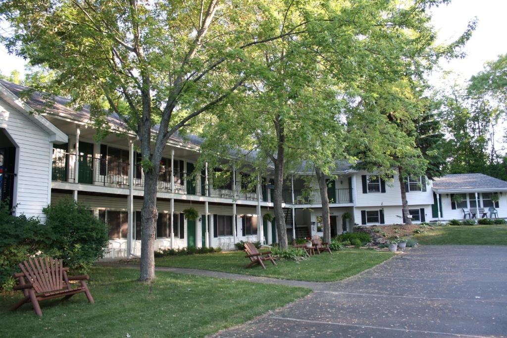 un grand bâtiment blanc avec des bancs devant lui dans l'établissement Parkside Inn, à Ellison Bay