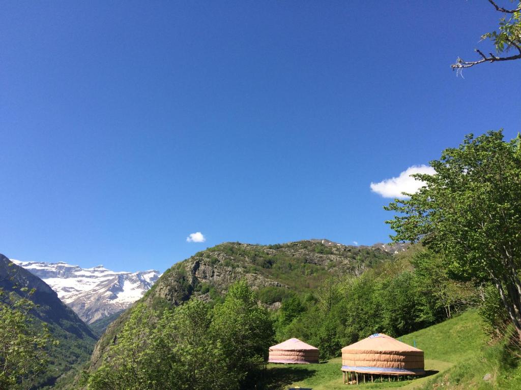 duas cabanas numa colina com montanhas ao fundo em Yourtes Mongoles Gavarnie em Gèdre