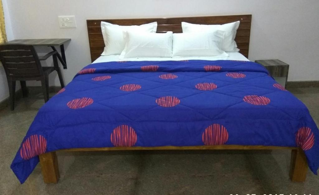 a blue bed with white pillows and a blue comforter at Aashraya Homestay in Mysore