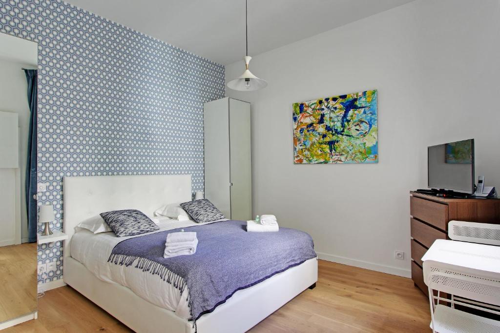 パリにあるPick a Flat's Apartment in Montmartre - Rue des Martyrs studioのベッドルーム1室(ベッド1台付)が備わります。壁には絵画が飾られています。
