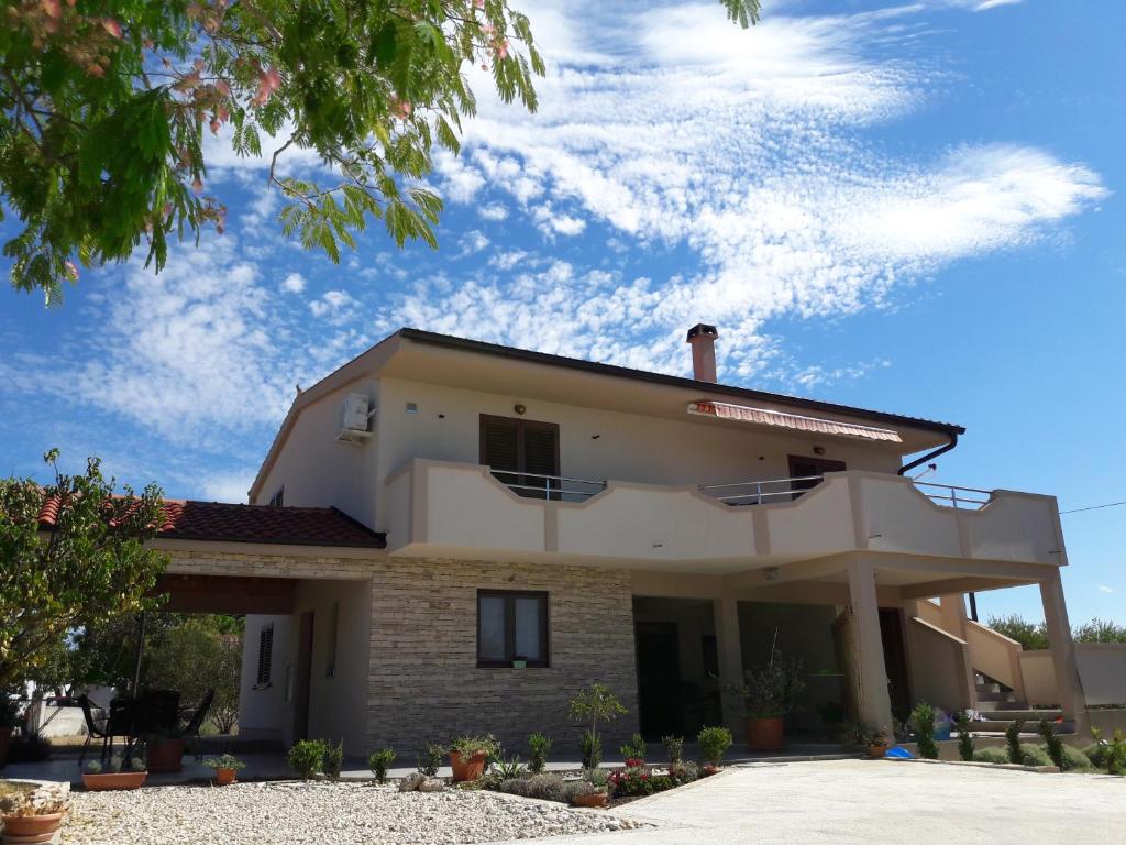 a large white house with a sky in the background at Apartmani Predovan in Vrsi