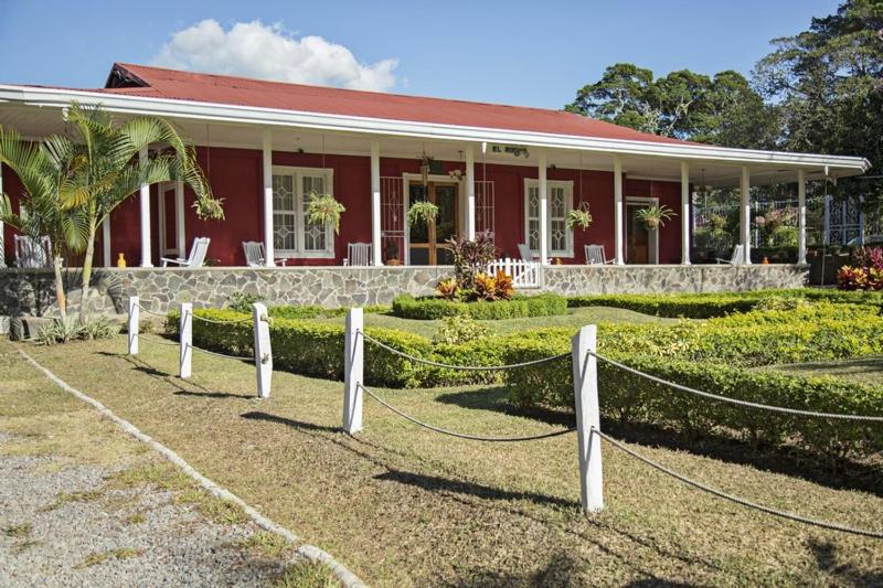 una casa roja con una valla delante en Hotel Hacienda El Rodeo en Rodeo